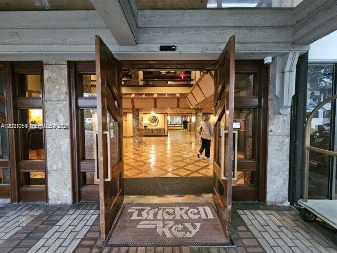 The entrance to a building features large wooden doors opening into a tiled lobby — 520 Brickell Key Dr # A1005, Miami FL 33131, MIAMI, FL