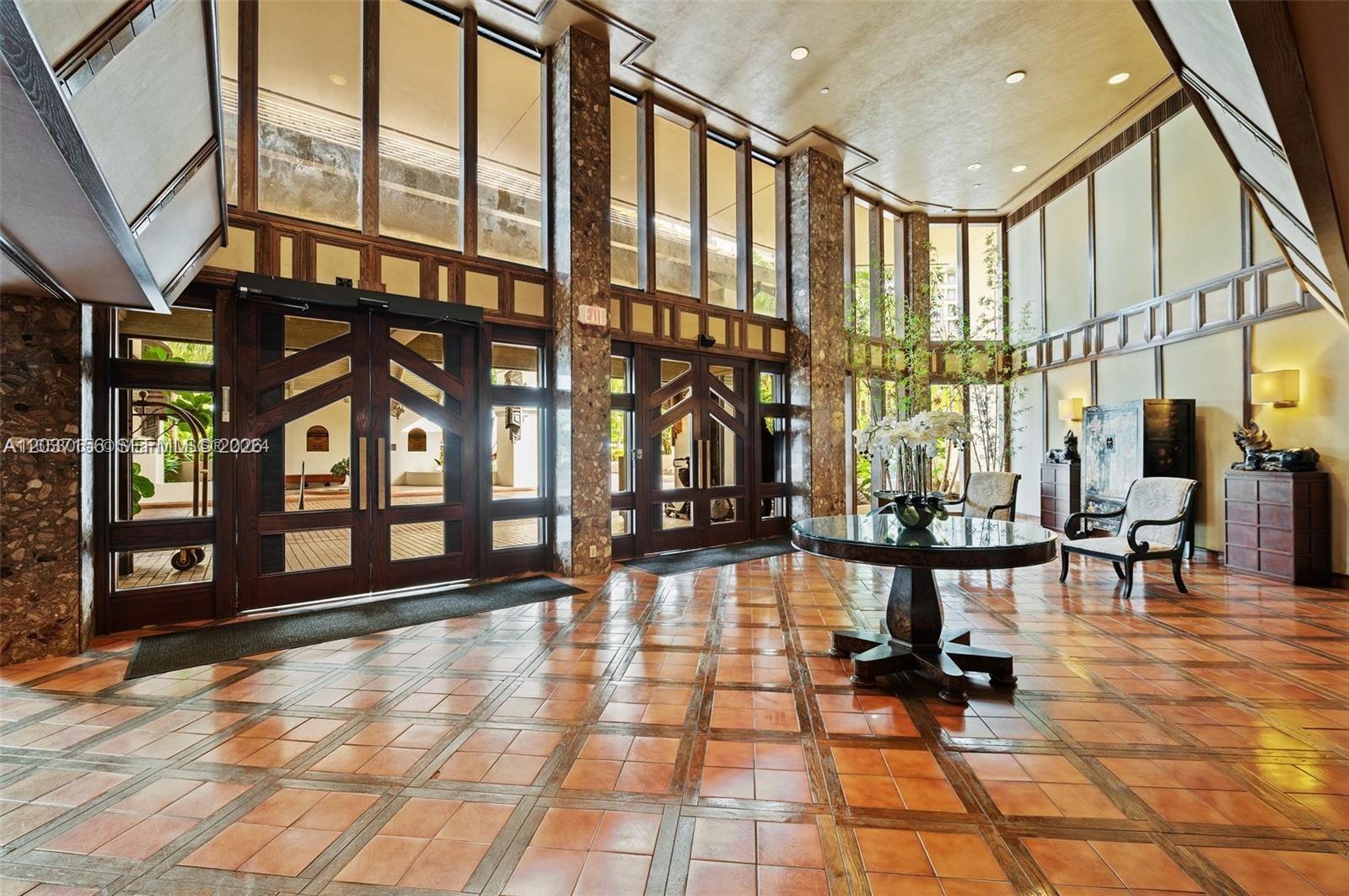 A spacious lobby features a tiled floor, large glass doors, and tall windows with stone pillars — 520 Brickell Key Dr # A1005, Miami FL 33131, MIAMI, FL