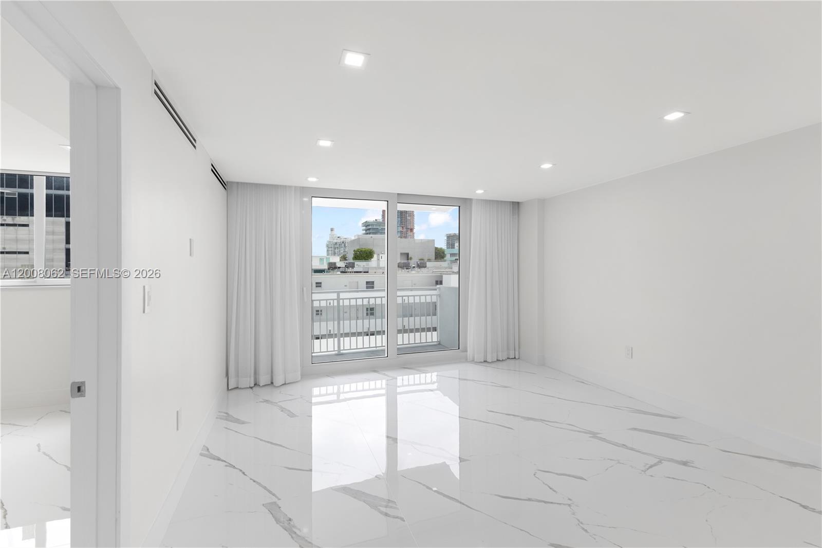 A bright, empty room features white marble-patterned tile flooring and a sliding glass balcony door — 345 Ocean Dr # 708, Miami Beach FL 33139, MIAMI BEACH, FL