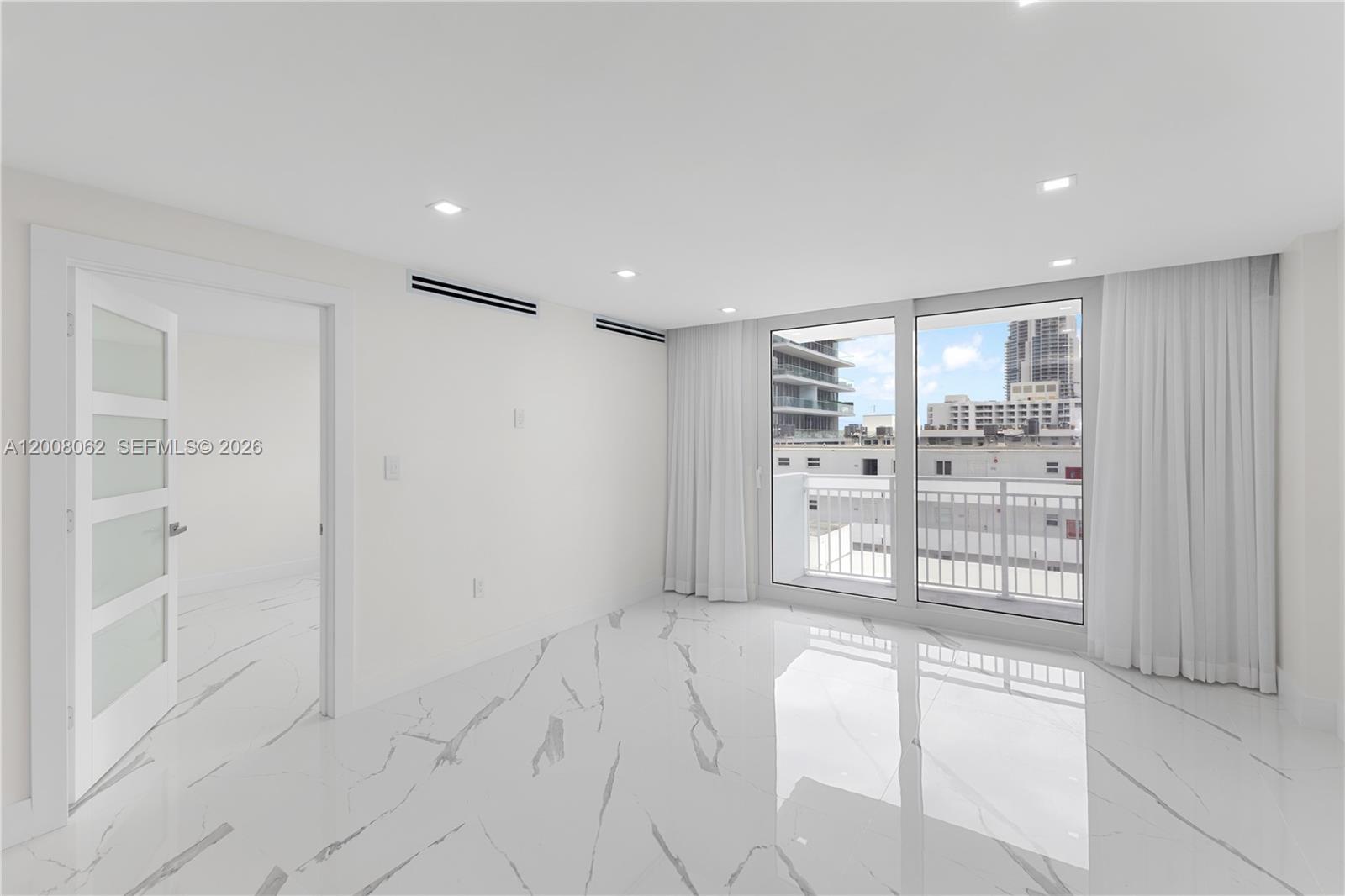 A bright, empty room features white marble-patterned tile floors, recessed lighting, and a balcony view — 345 Ocean Dr # 708, Miami Beach FL 33139, MIAMI BEACH, FL