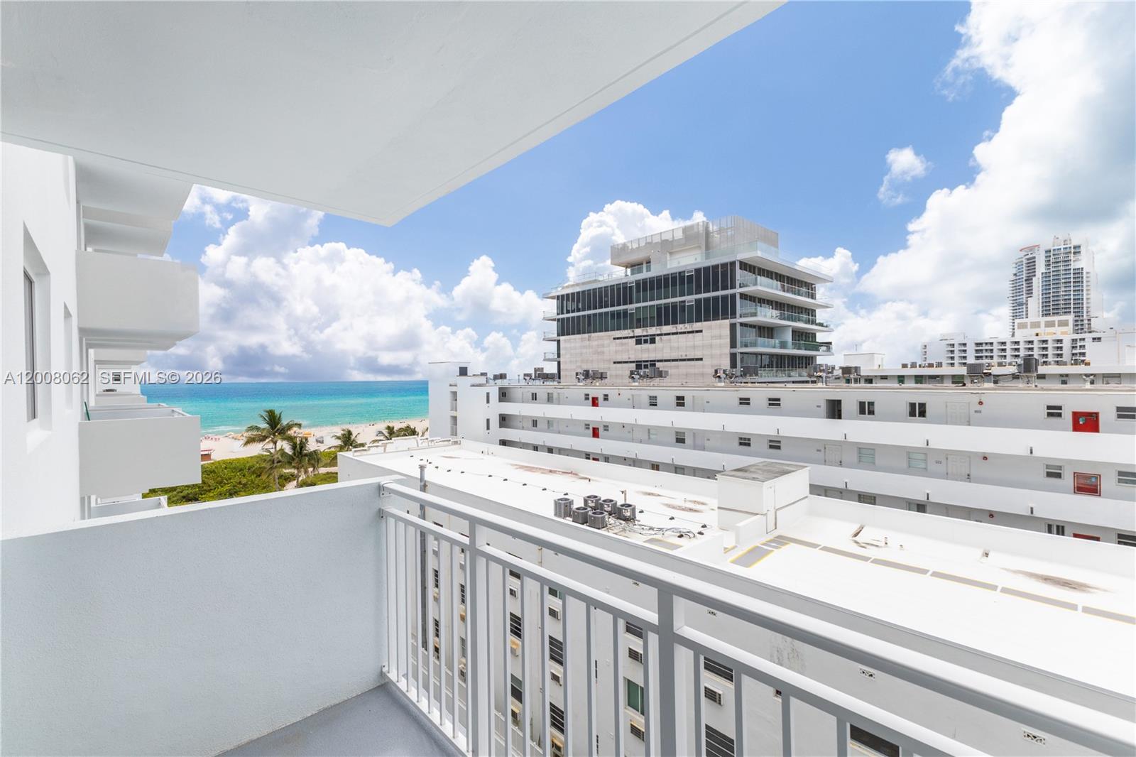 A balcony overlooks a beach, the ocean, and surrounding white apartment buildings under a blue sky — 345 Ocean Dr # 708, Miami Beach FL 33139, MIAMI BEACH, FL