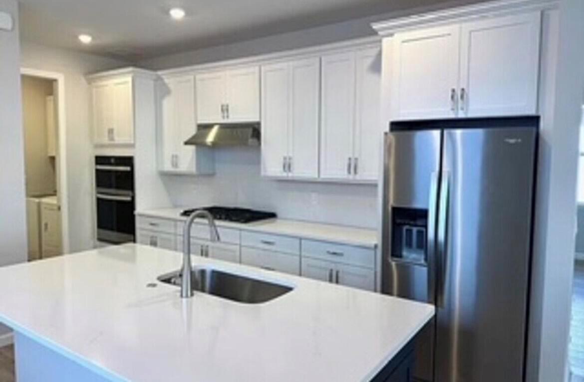 A modern kitchen features white cabinets, stainless steel appliances, and a large white island — 4520 Jolly Roger Manor, Vero Beach FL 32967, VERO BEACH, FL