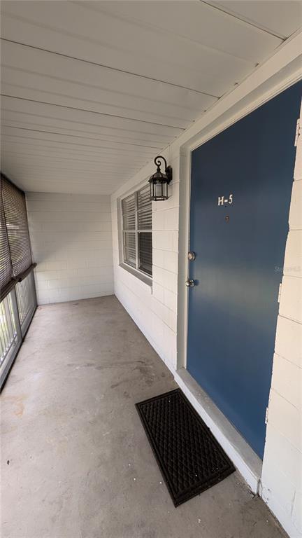 A covered concrete porch leads to a blue front door labeled H-5 — 700 E AIRPORT BOULEVARD UNIT H5, SANFORD, FL