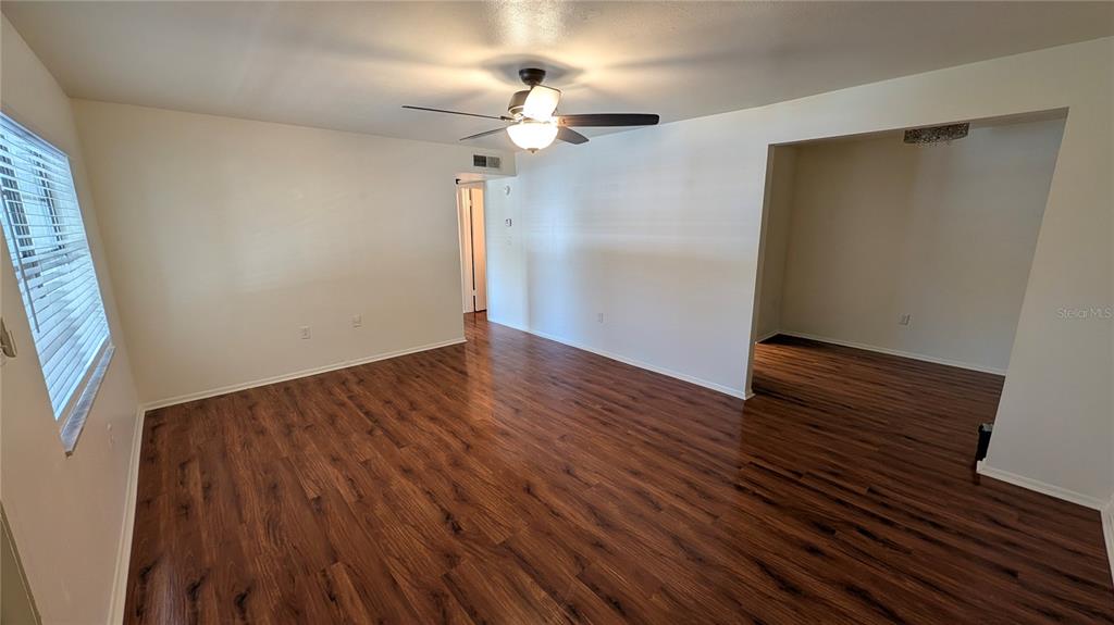 An empty room features wood-look laminate flooring, white walls, and a ceiling fan — 700 E AIRPORT BOULEVARD UNIT H5, SANFORD, FL