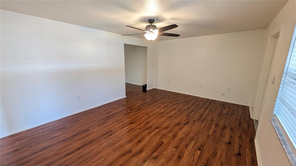 An empty room features wood-look laminate flooring, white walls, and a ceiling fan — 700 E AIRPORT BOULEVARD UNIT H5, SANFORD, FL