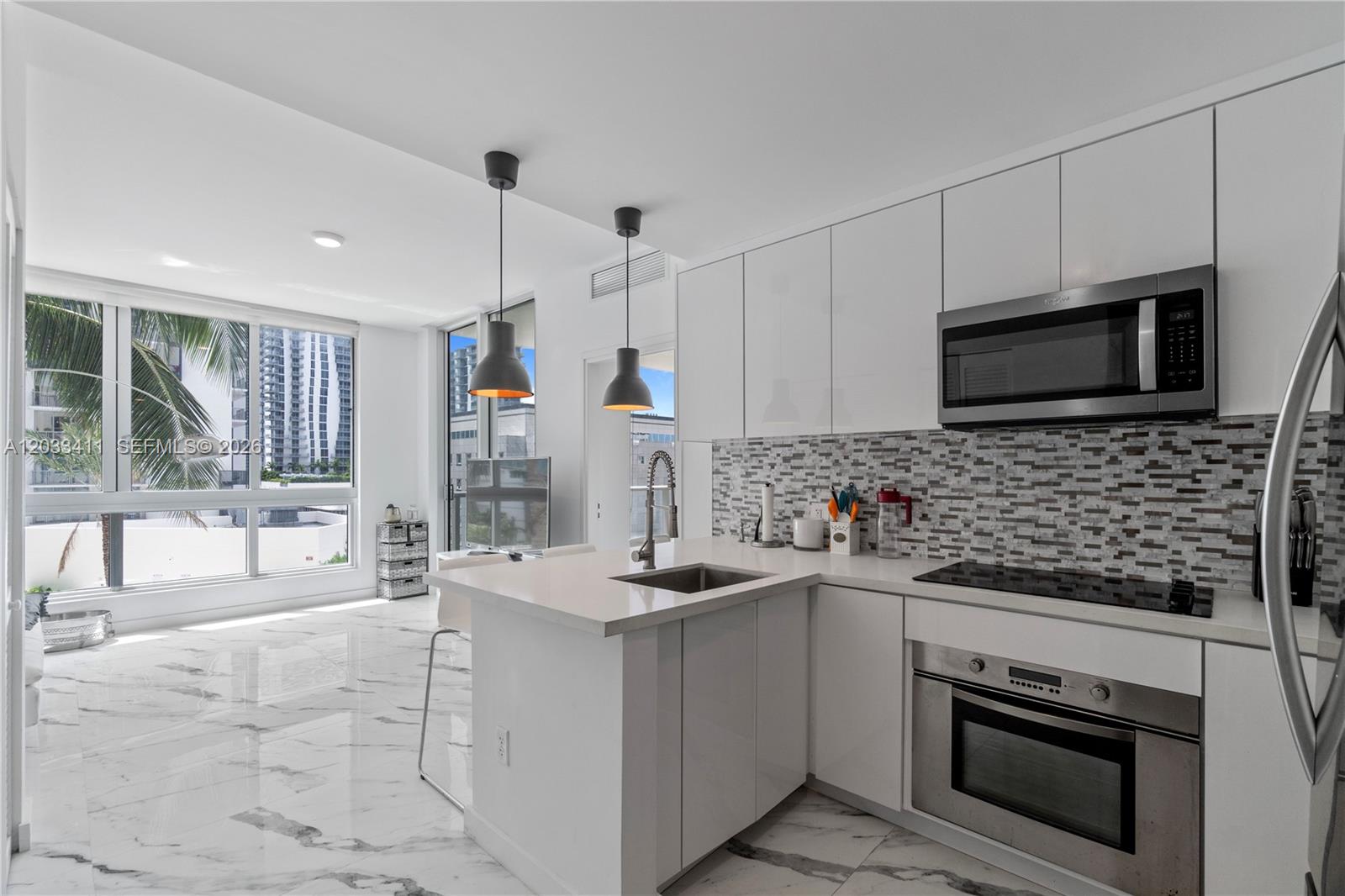 A modern kitchen features white cabinetry, marble-patterned tile floors, and a view of city buildings — 300 S Biscayne Blvd # 1411, Miami FL 33131, MIAMI, FL