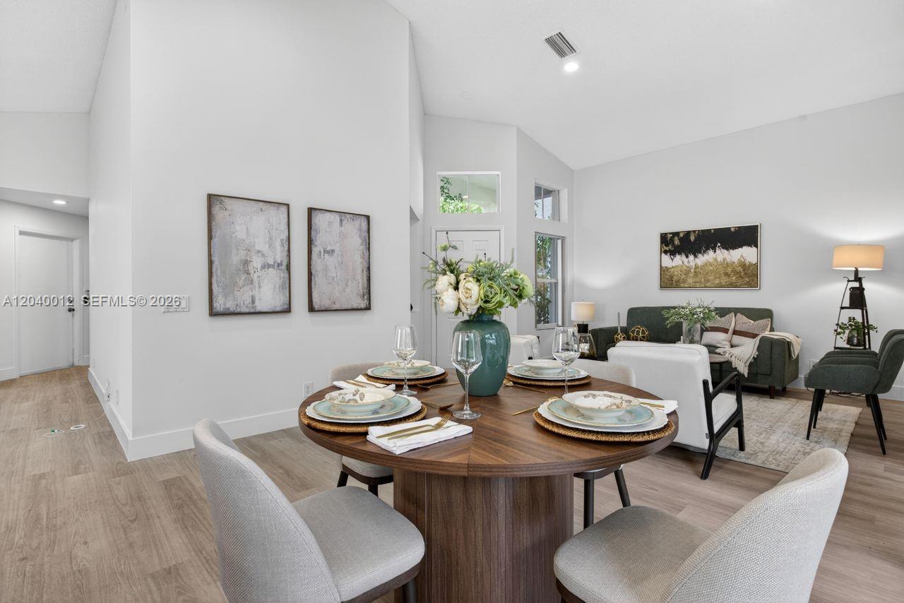 A dining area with a round wooden table sits in front of a living room — 116 W Bayridge Dr, Weston FL 33326, WESTON, FL