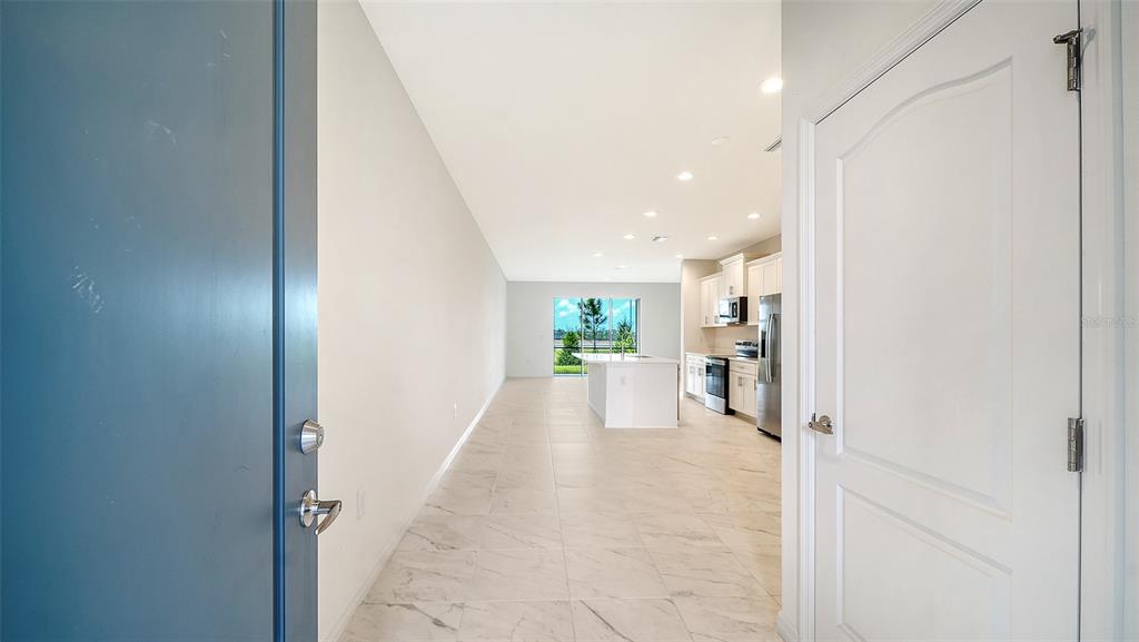 A view from an open doorway into a bright, tiled kitchen and living area — 2357 WASHINGTON PALM COURT, BRADENTON, FL