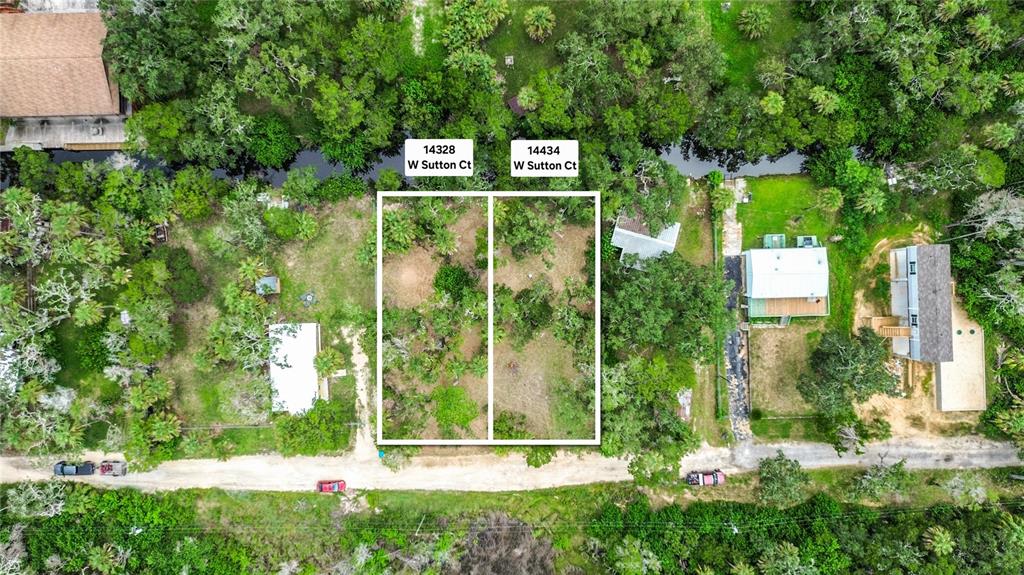This aerial view shows two adjacent vacant lots outlined in white along a dirt road — 14334 W SUTTON COURT, CRYSTAL RIVER, FL