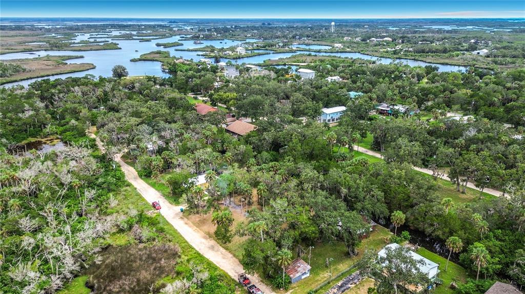 An aerial view shows a dirt road winding through a wooded area with scattered houses — 14334 W SUTTON COURT, CRYSTAL RIVER, FL