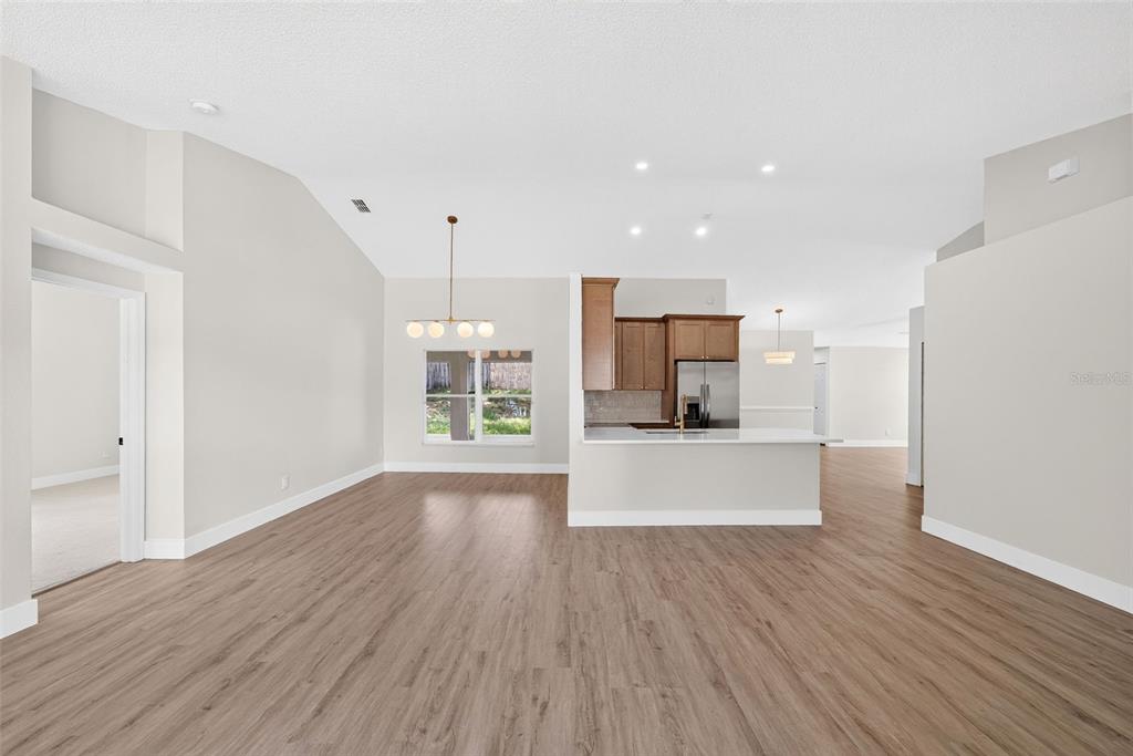 An open-concept living and dining area features light wood-look flooring and a modern kitchen — 294 LAKE DOE BOULEVARD, APOPKA, FL