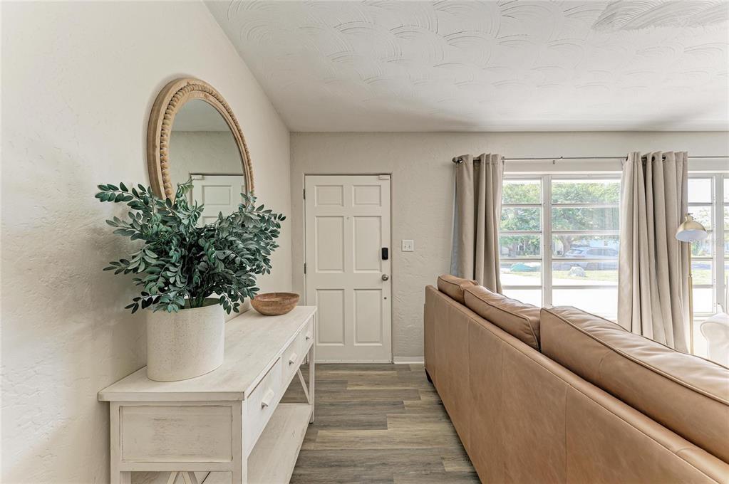 A living room features a leather sofa, two armchairs, a television, and wood-look flooring — 120 60TH STREET W, BRADENTON, FL