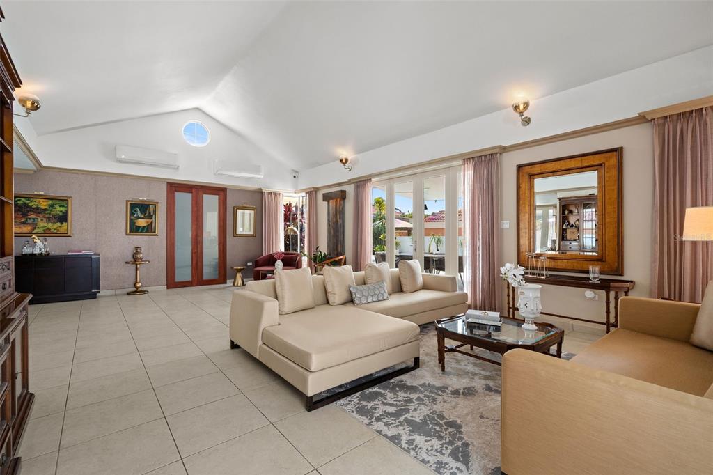 A spacious living room features a vaulted ceiling, beige sectional sofa, tile flooring, and glass doors — 377 CORREDOR DE LA ARBOLEDA, DORADO, PR