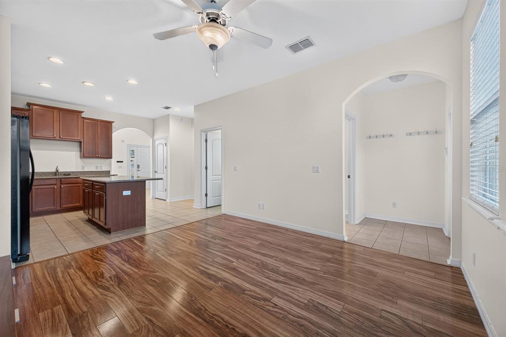 A kitchen with wood cabinets and an island opens into a dining area with flooring — 7516 BENTONSHIRE AVENUE, WINDERMERE, FL