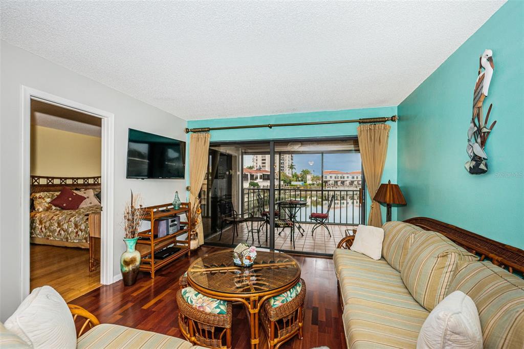 A living room features a striped sofa, rattan coffee table, and sliding doors to a balcony — 6281 BAHIA DEL MAR BOULEVARD UNIT 208, ST PETERSBURG, FL