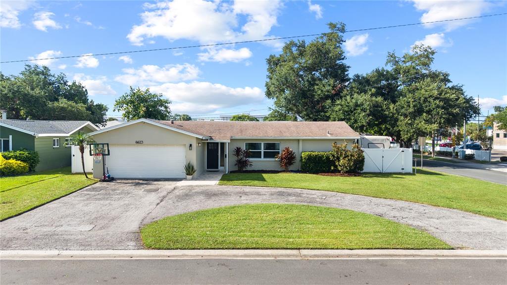 A single-story house with a white garage, a curved driveway, and a green lawn — 6623 12TH TERRACE N, ST PETERSBURG, FL