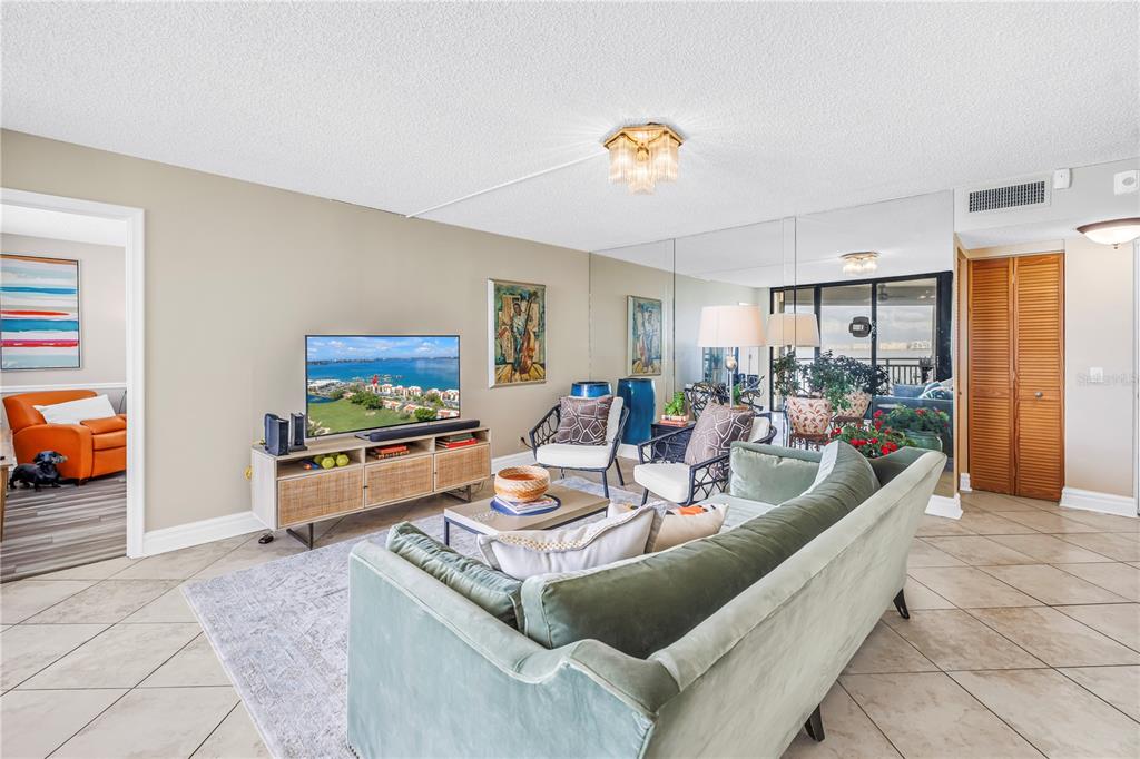 A living room features tile floors, a green sofa, and a balcony with water views — 5825 PUERTA DEL SOL BOULEVARD S UNIT 464, ST PETERSBURG, FL