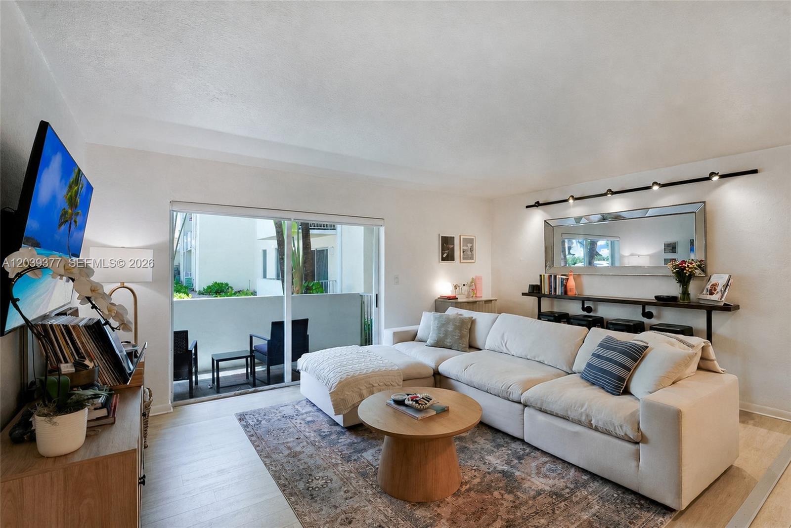 A living room features a white sectional sofa, a round wooden coffee table, and a balcony — 8950 SW 69th Ct # 109, Pinecrest FL 33156, PINECREST, FL