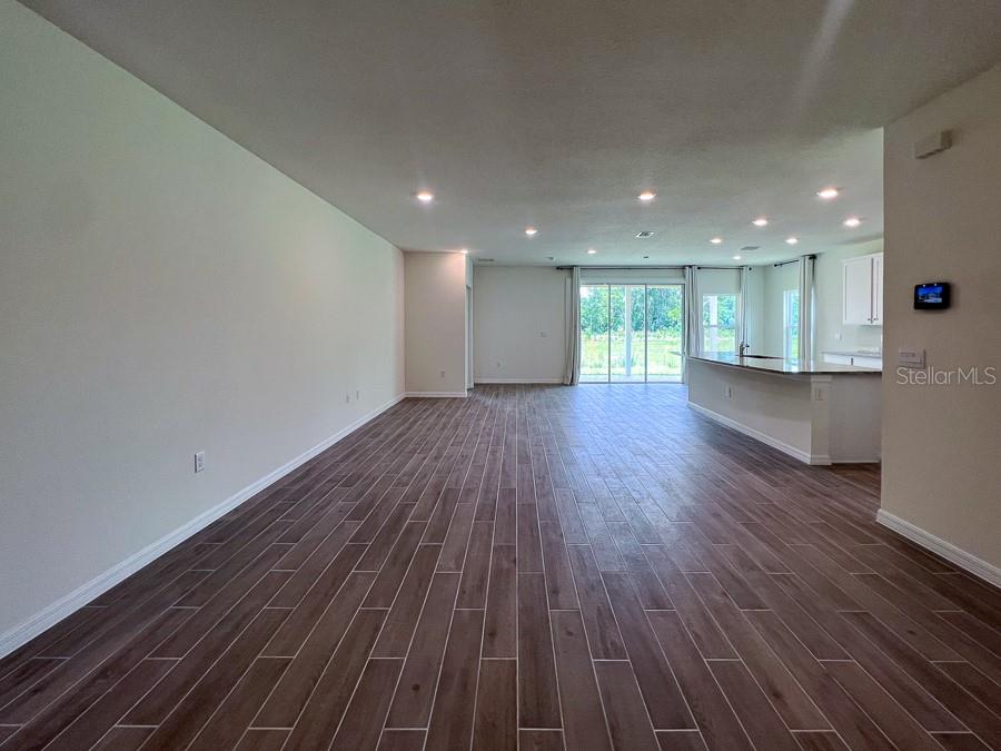 An open-concept living area features wood-look tile flooring and a kitchen with a breakfast bar — 1315 NW 132ND CIRCLE, NEWBERRY, FL