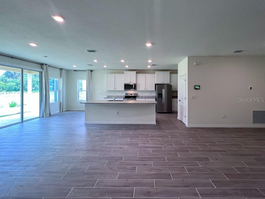 An open-concept kitchen features white cabinetry, stainless steel appliances, a large island, and tile flooring — 1315 NW 132ND CIRCLE, NEWBERRY, FL