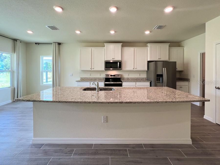 A kitchen featuring white cabinets, granite countertops, a large island, and stainless steel appliances — 1315 NW 132ND CIRCLE, NEWBERRY, FL