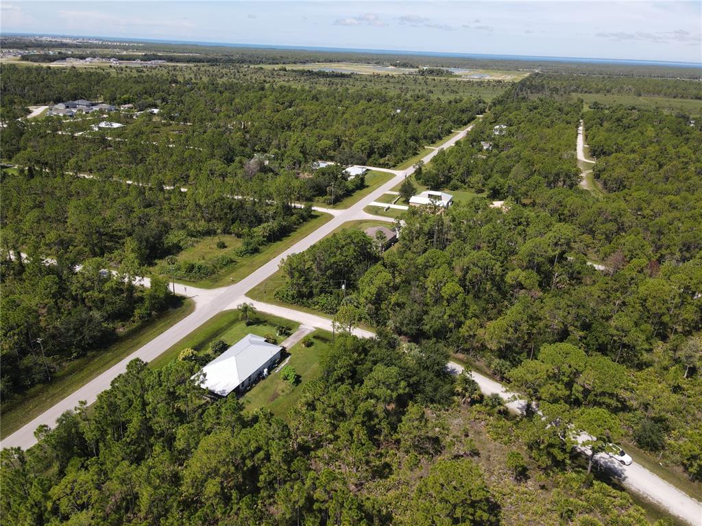 An aerial view shows a house with a white roof surrounded by dense forest — 12260 ESCUELA DRIVE, PUNTA GORDA, FL