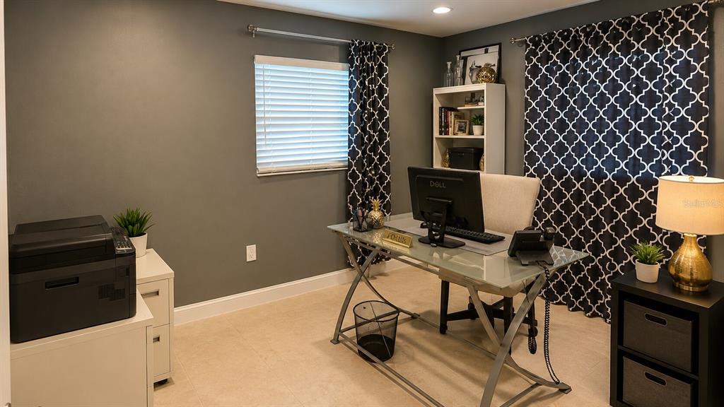 A home office features a glass-top desk, a computer, a bookshelf, and patterned curtains — 150 W 11TH STREET, CHULUOTA, FL