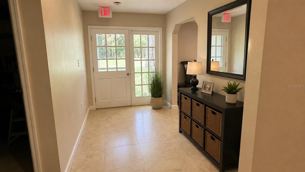 An entryway features tile flooring, a dark console table with baskets, and glass-paneled double doors — 150 W 11TH STREET, CHULUOTA, FL