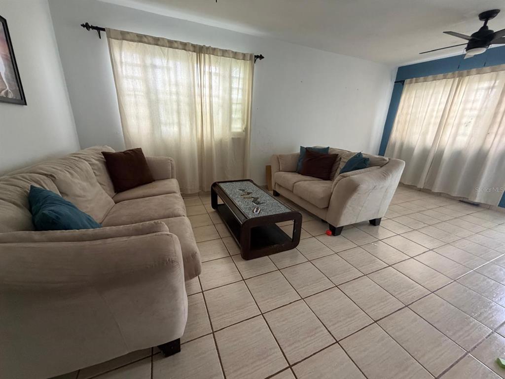 A living room features two beige sofas, a coffee table, and tiled flooring — Calle 2 BLQ C, NUMERO 72, RIO GRANDE, PR