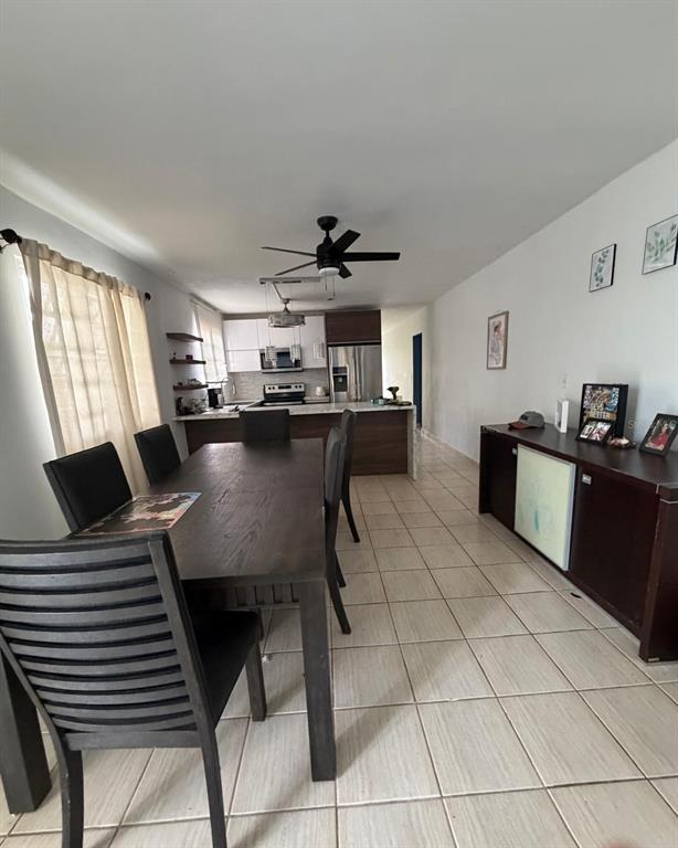 A dining area with a dark wood table and chairs leads into an open kitchen — Calle 2 BLQ C, NUMERO 72, RIO GRANDE, PR