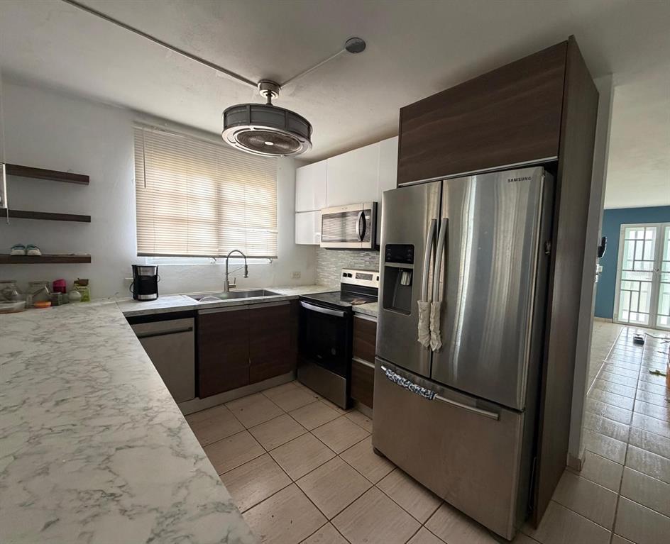 A kitchen features stainless steel appliances, dark wood cabinets, and white marble-patterned countertops — Calle 2 BLQ C, NUMERO 72, RIO GRANDE, PR