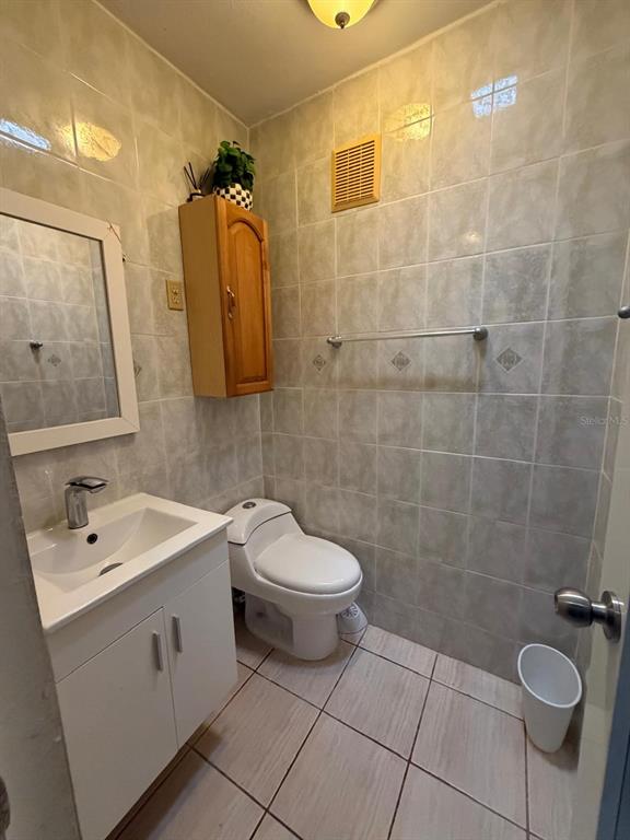 A small bathroom features light-colored wall and floor tiles, a white vanity, and a toilet — Calle 2 BLQ C, NUMERO 72, RIO GRANDE, PR