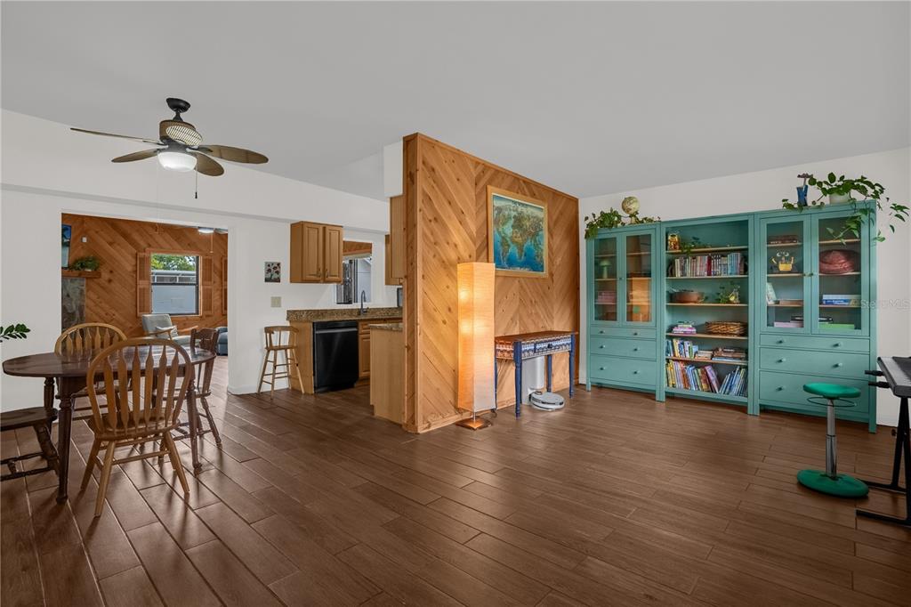 A living and dining area features wood-look tile flooring, a wood-paneled accent wall, and cabinetry — 125 E LAUREN COURT, FERN PARK, FL