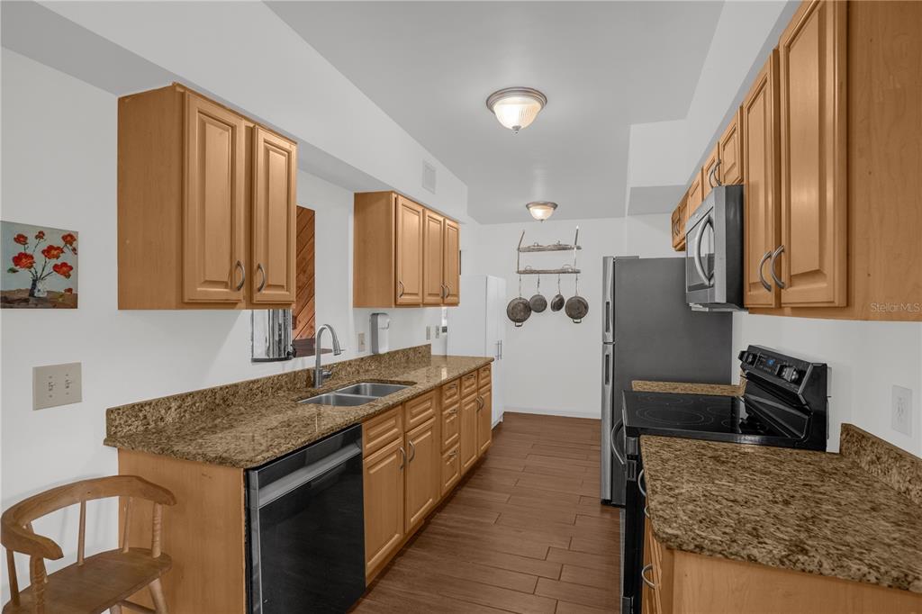 A kitchen with light wood cabinets, granite countertops, stainless steel appliances, and wood-look tile flooring — 125 E LAUREN COURT, FERN PARK, FL