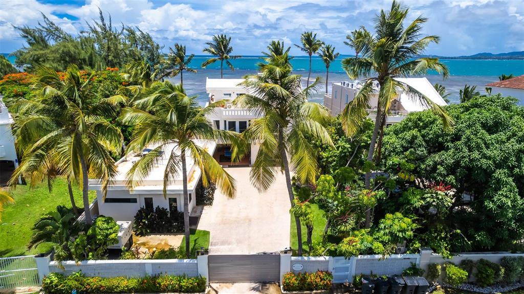 An aerial view shows a white house with palm trees and a gated driveway near water — Lot G Km 2.1 Carr. 968 LAS PICUAS, RIO GRANDE, PR