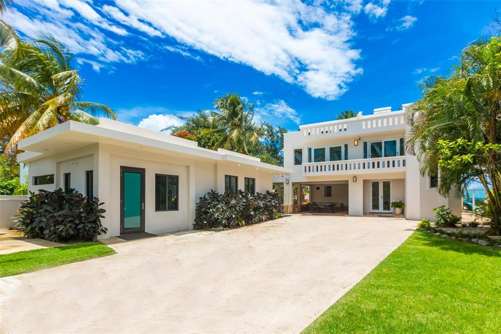 A two-story white house with a flat roof and a paved driveway under a blue sky — Lot G Km 2.1 Carr. 968 LAS PICUAS, RIO GRANDE, PR
