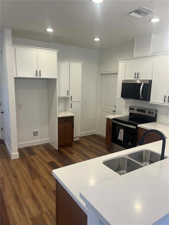 A kitchen features white upper cabinets, wood lower cabinets, stainless steel appliances, and quartz countertops — 7848 SE 70TH AVENUE, TRENTON, FL