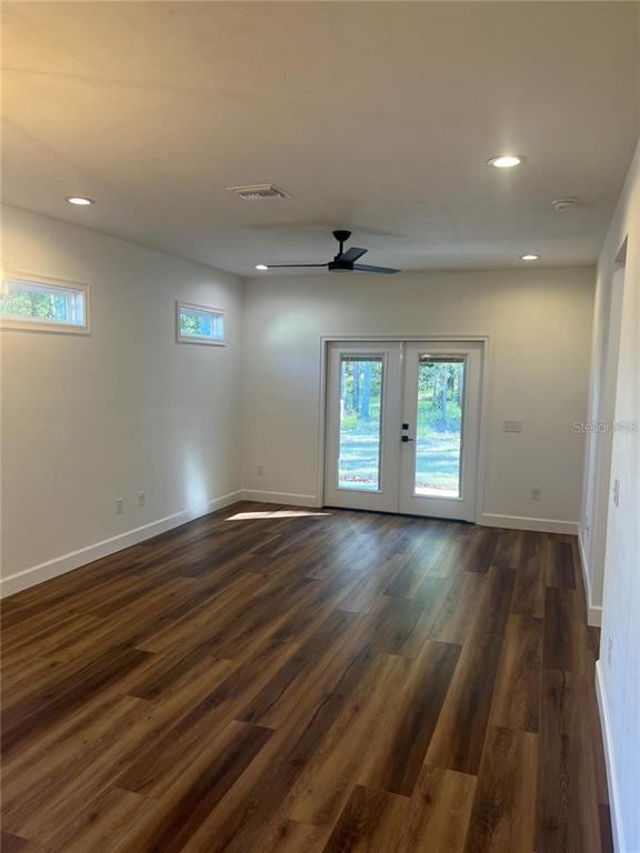 A bright room features wood-look flooring, a ceiling fan, and double glass doors leading outside — 7848 SE 70TH AVENUE, TRENTON, FL