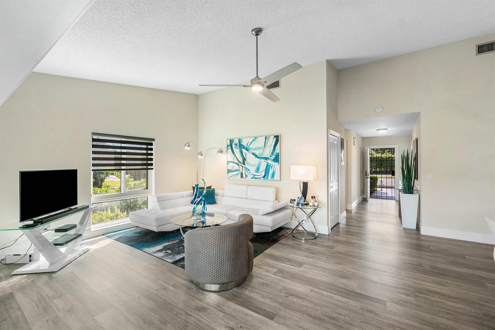 A living room features a white sectional sofa, a gray armchair, and wood-look flooring — 732 Lago Road, Delray Beach FL 33445, DELRAY BEACH, FL