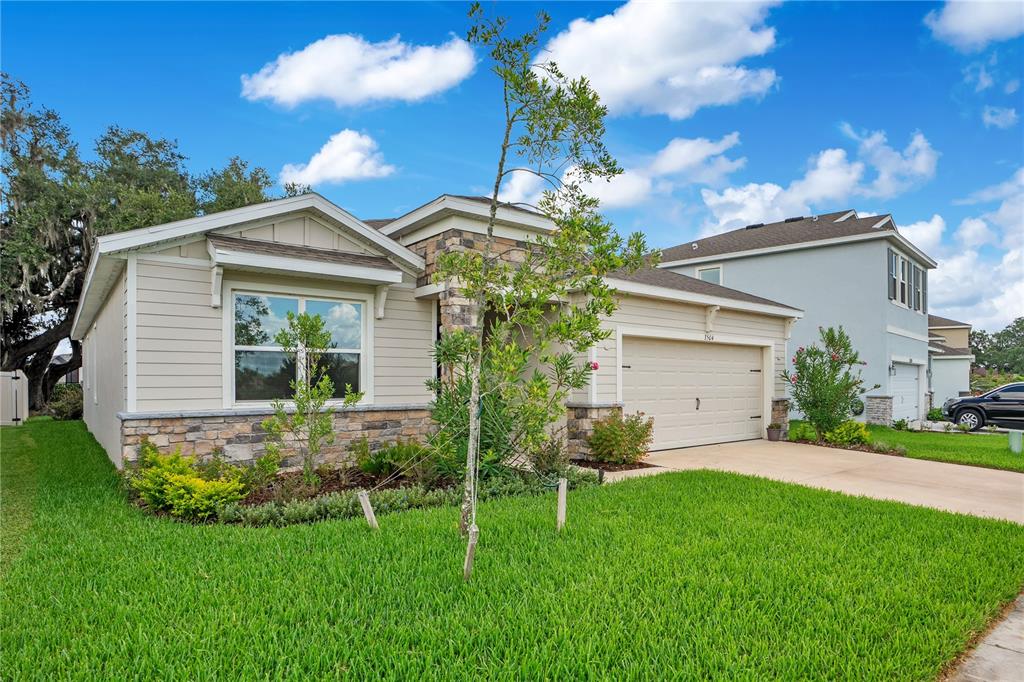 A single-story house with tan siding, stone accents, and a two-car garage — 3504 CRESCENT PEAK WAY, PLANT CITY, FL