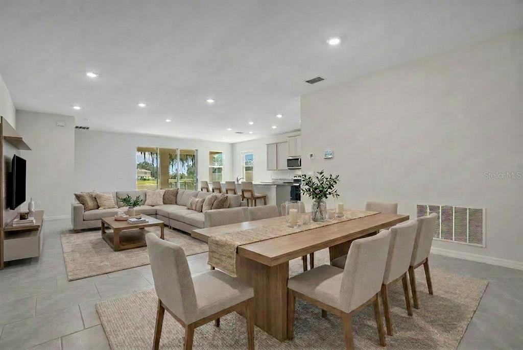 An open-concept living and dining area features neutral furniture, tile flooring, and a kitchen island — 3504 CRESCENT PEAK WAY, PLANT CITY, FL