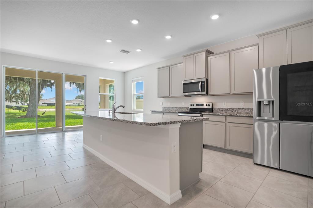 A kitchen features light gray cabinets, granite countertops, stainless steel appliances, and tile flooring — 3504 CRESCENT PEAK WAY, PLANT CITY, FL