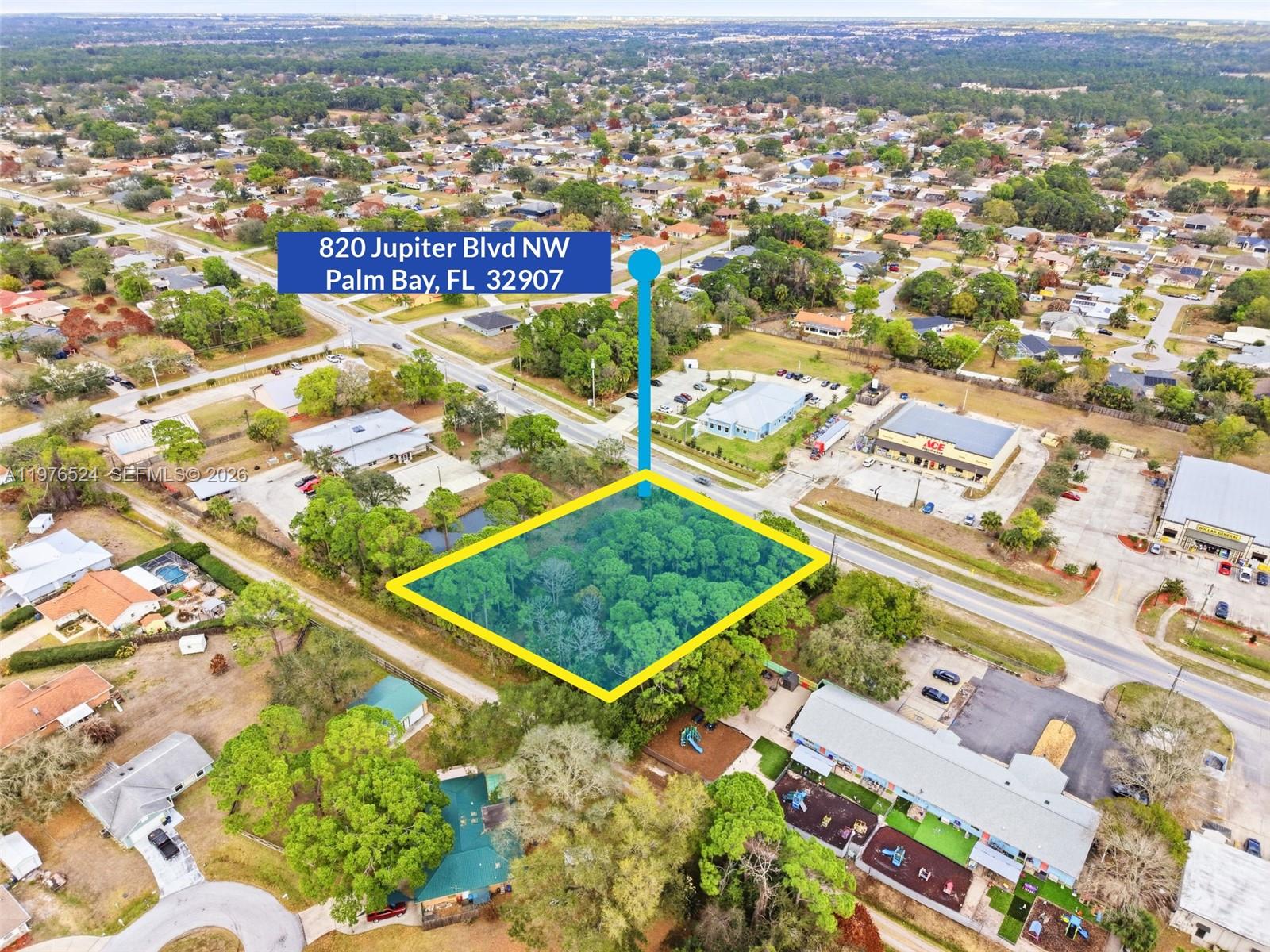 An aerial view shows a rectangular, wooded vacant lot highlighted in yellow near commercial buildings — 820 Jupiter Blvd NW, Palm Bay FL 32907, PALM BAY, FL
