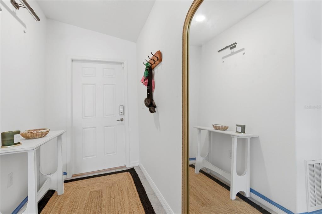 An entryway features a white door, a wooden coat rack, a console table, and a mirror — 12611 LEMON PEPPER DRIVE, RIVERVIEW, FL