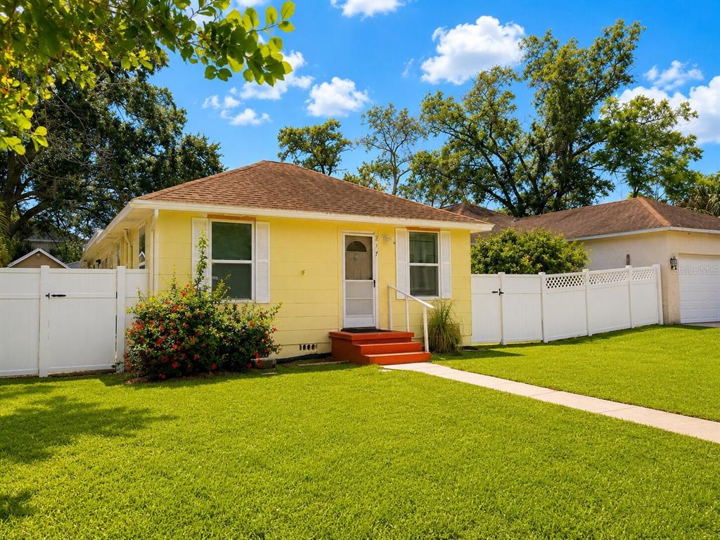 A yellow single-story house with a white fence and a red front porch — 217 50TH TER N, ST PETERSBURG, FL