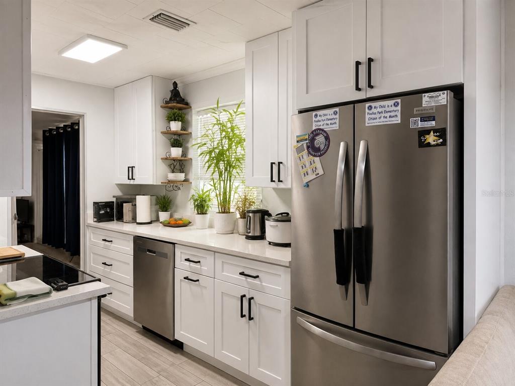 A modern kitchen features white cabinets, stainless steel appliances, and a light-colored countertop — 217 50TH TER N, ST PETERSBURG, FL