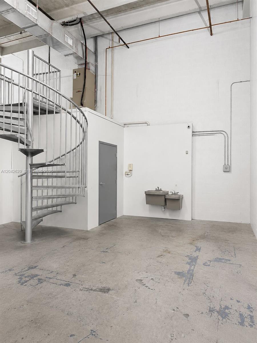 A room with a metal spiral staircase, a gray door, and a wall-mounted water fountain — 6020 NW 99th Ave # 205, Doral FL 33178, DORAL, FL