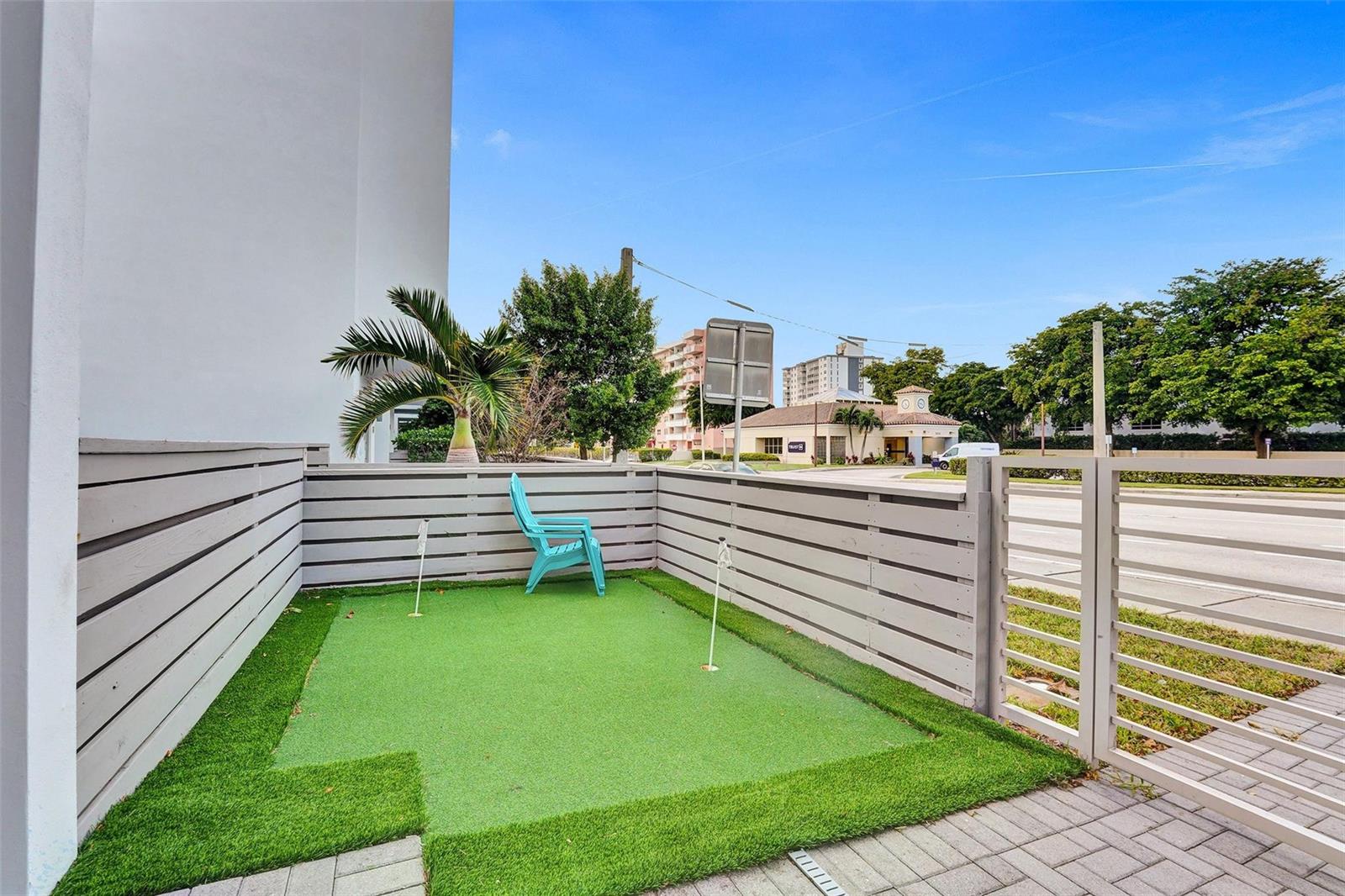 A small outdoor putting green with two holes sits inside a fenced patio area — 1371 N Ocean Boulevard, Pompano Beach FL 33062, POMPANO BEACH, FL