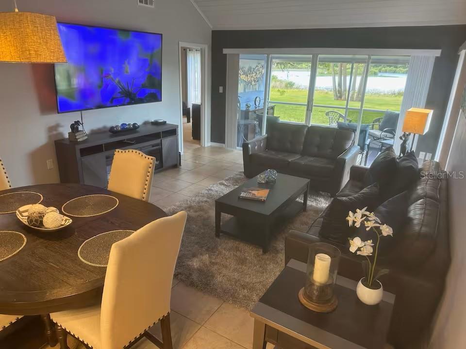 A living and dining area features dark furniture, a gray area rug, and sliding glass doors — 1144 VILLA LANE UNIT 100, APOPKA, FL