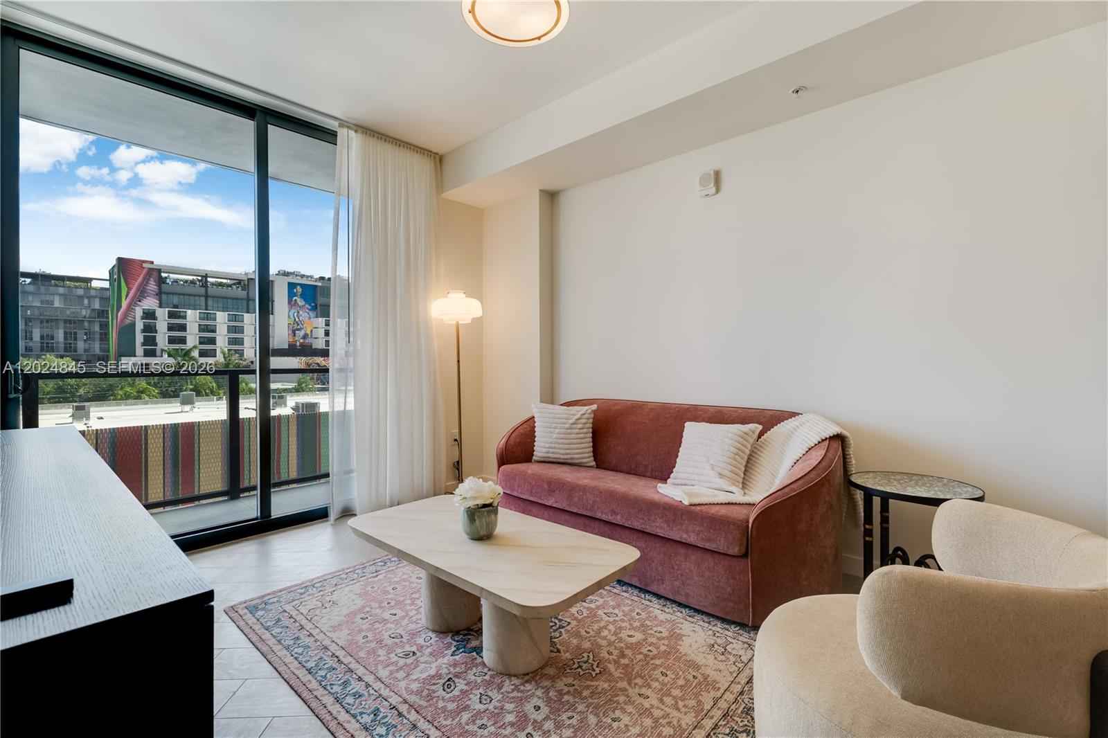 A living room features a pink sofa, a stone coffee table, and a balcony view — 2700 NW 2nd Ave # 309, Miami FL 33127, MIAMI, FL